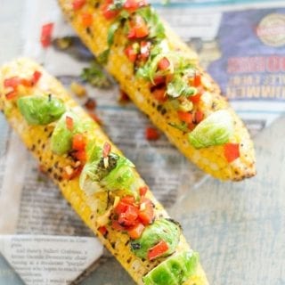 Overhead view of loaded grilled corn on the cob with brussles sprouts and bell pepper
