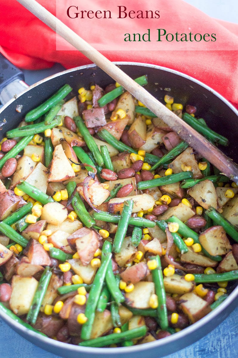 Overhead view of a pan filled with cooked green beans, potatoes, corn and red kidney beans