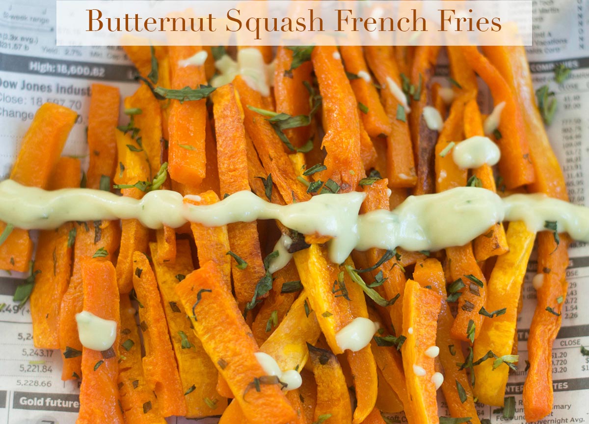 Overhead view of butternut squash french fries on a newspaper and drizzled with Avocado dressing