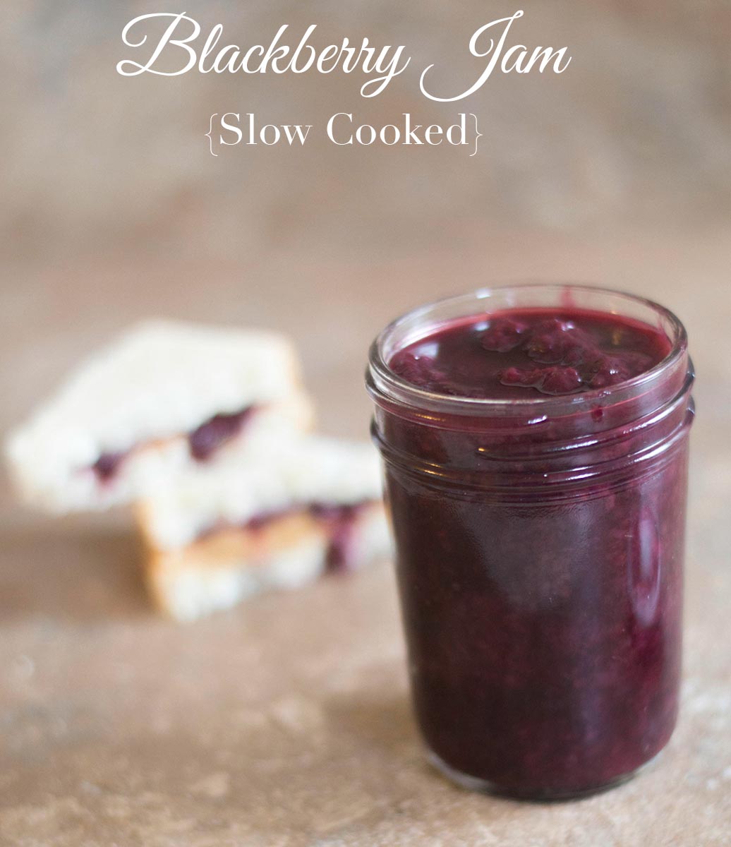 Front view of a small mason jar filled with blackberry jam. In the back 2 small pb&j recipes are stacked on top of each other