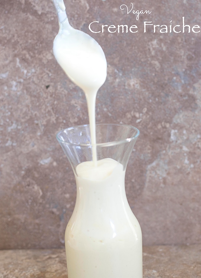 A Spoon Filled with Creme Fraiche is Slowly Dripping Into a Glass Jar Filled with More Vegan Creme Fraiche