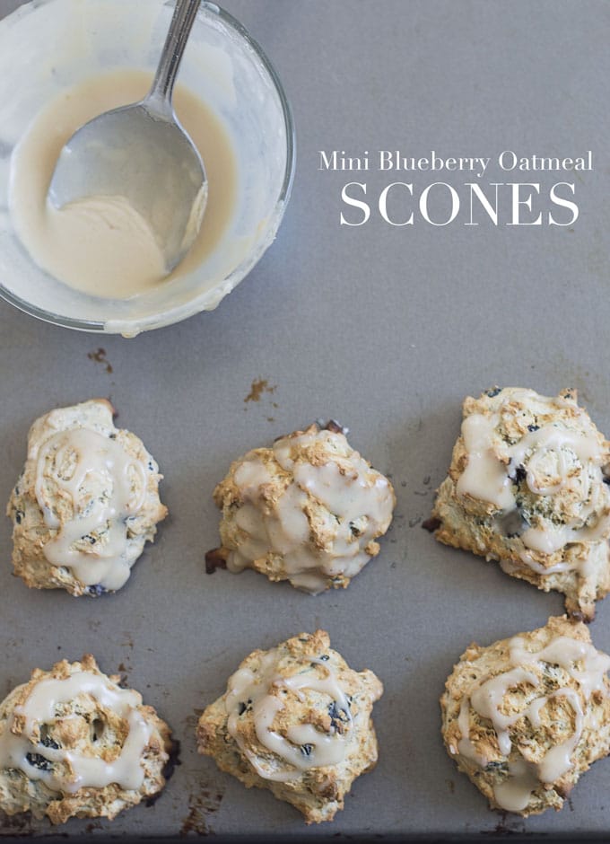 Overhead View of Six Mini Vegan Oatmeal Scones are on a Baking Tray.  They are Arranged in 2 Rows at the Bottom of the Photo.  On the Top Left of the Picture, a Transparent Bowl with the Creamy Dressing and a Wide Steel Spoon is Visible