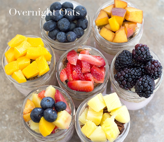 Overhead View of 6 Mason Jars Arranged in a Circle and 1 jar in the Middle. Each Jar is Topped With Fruits