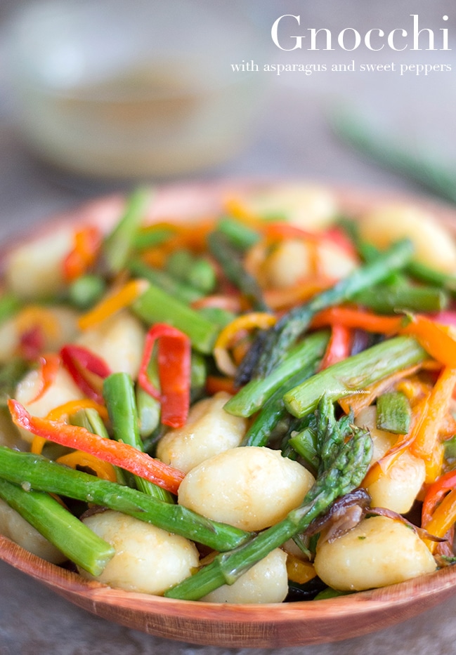 Closeup view of Gnocchi and vegetables in a brown bowl.