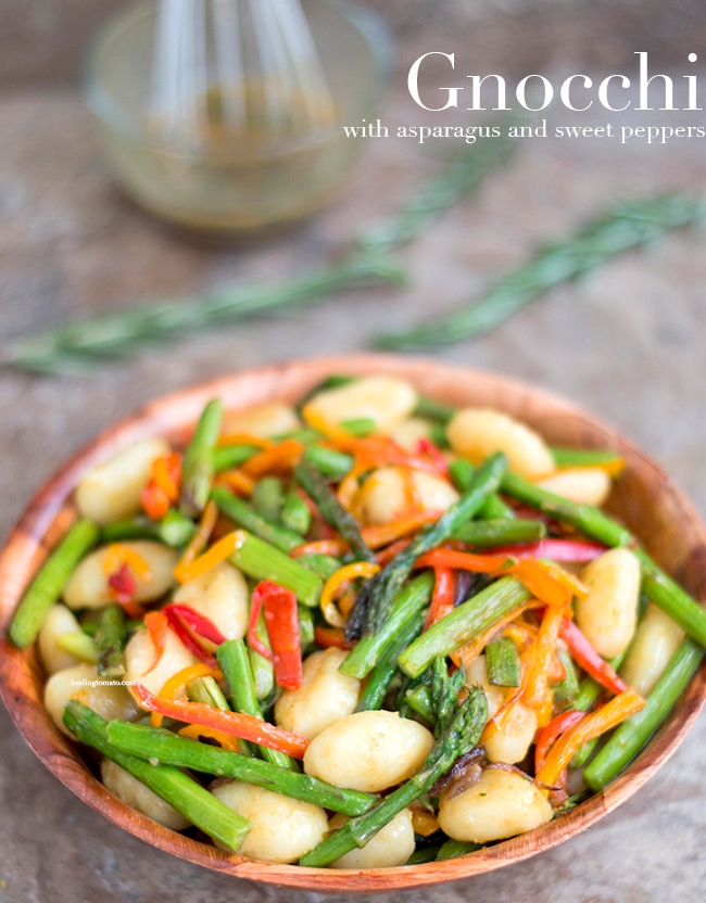 Top view of a brown bowl with Gnocchi, asparagus and red bell peppers