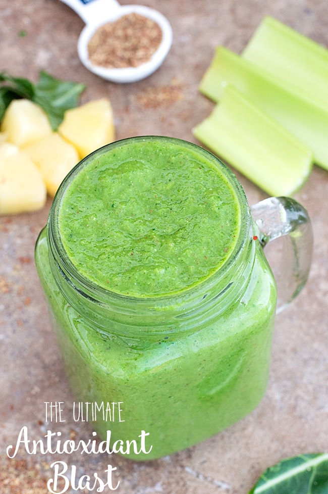 Top view of a green smoothie drink in a glass mug.  Pineapple chunks and celery in the background