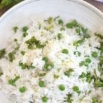 Overhead view of a white bowl with coconut rice and peas