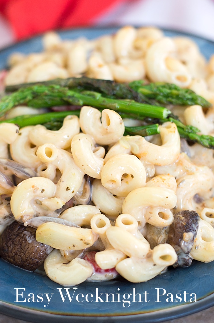 Closeup view of Cooked Elbow Pasta in Alfredo Sauce With Cooked Veggies and Topped with Long Sprigs of Asparagus - Easy Weeknight Pasta