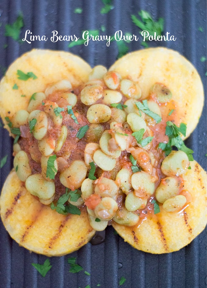 Overhead Photo of Lima Beans in a Light Tomato Gravy Topped on Four Small Rounds of Polenta Over a Black Calphalon Square Grill. Grill Marks Visible on the Polenta