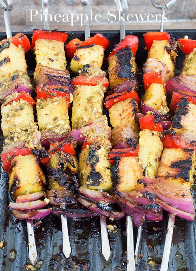 Overhead View of 6 Metal Skewers Filled with Fruits and Veggies. Each Skewer has a Grilled Pineapple Piece, a Red Bell Pepper and a Red Onion. Each Skewer has This Arrangement 3 Times - Pineapple Skewers