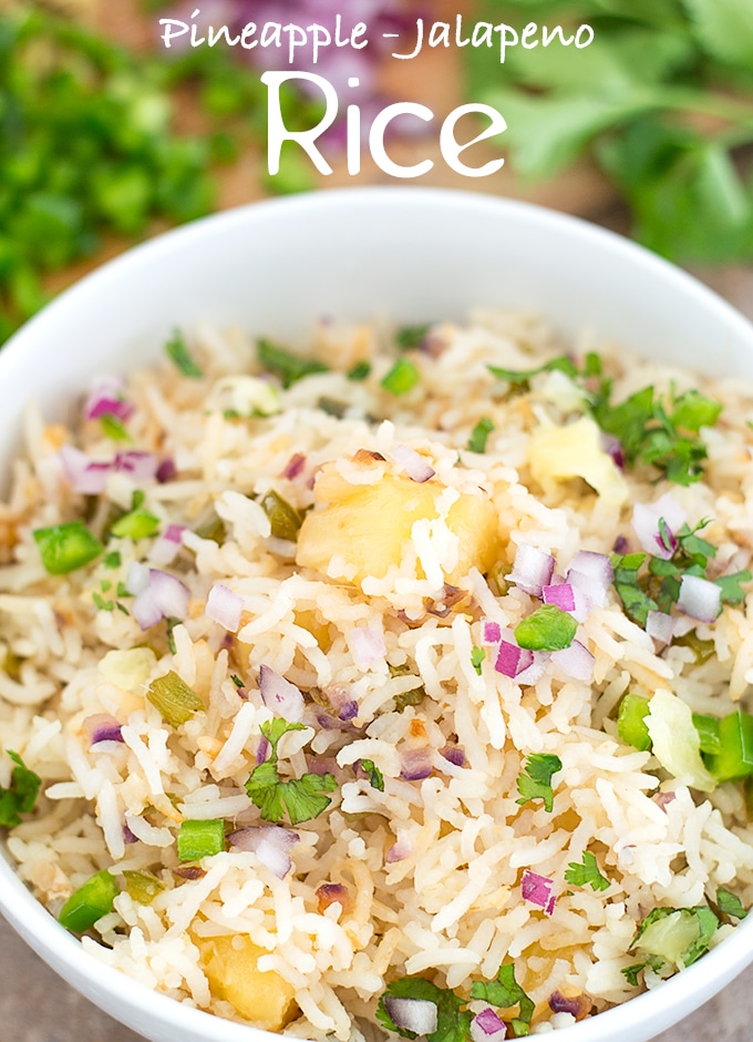 Overhead View of a White Bowl Filled with Cooked Rice, Pineapple, Jalapeno, Red Onions and Cilantro. In the Background, Chopped Jalapeno, Red Onions and Cilantro leaves are Visible - Pineapple fried Rice