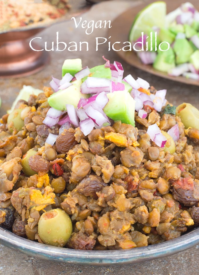 Front View of a Plate Filled to the Brim with Cuban Picadillo. In the Middle, its Garnished with Olives, Avocado, Raisins and Red Onions