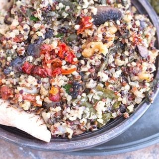 Closeup View of a Rustic Bowl Filled with Cooked Quinoa, Mushrooms, Sundried Tomatoes, Kale and Walnuts