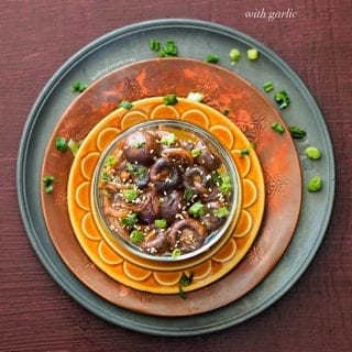 Roasted Mushrooms with Garlic in a bowl placed on 3 different colored plates.