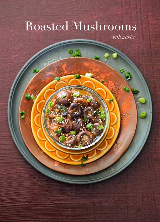 Roasted Mushrooms with Garlic in a bowl placed on 3 different colored plates. Garnished with green onions