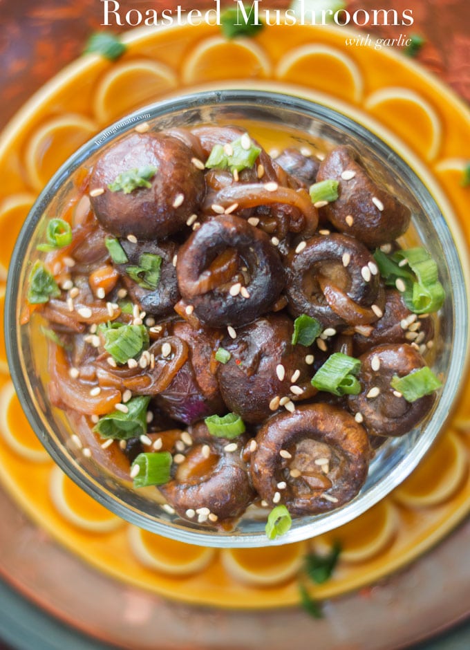 Roasted Mushrooms with Garlic in a clear bowl garnished with green onions and sesame seeds