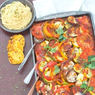 Overhead view of a Sheet Pan Filled With Ratatouille and 3 Spoons Coming Out at an Angle. A Grey Plate with Cooked Spaghetti is Visible on the Top