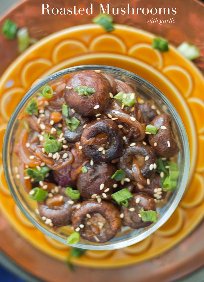 Roasted Mushrooms with Garlic in a clear bowl garnished with green onions and sesame seeds