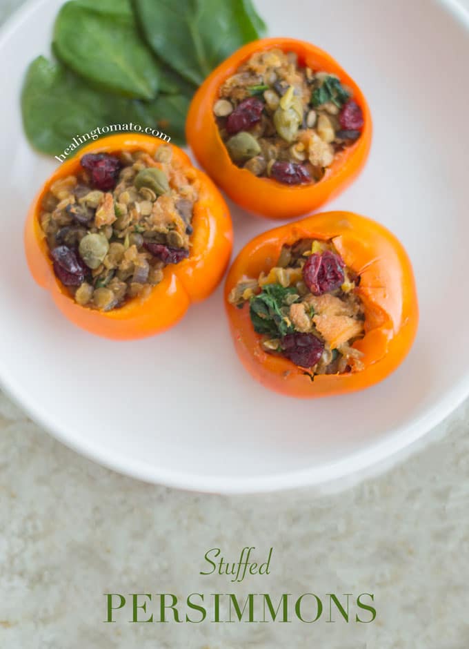 Three Stuffed Persimmons on a white plate with spinach leaves