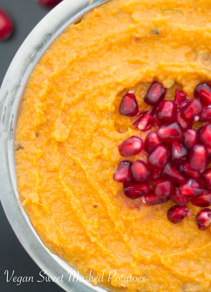 Closeup view of a steel bowl with vegan mashed sweet potatoes with pomegranate in the middle