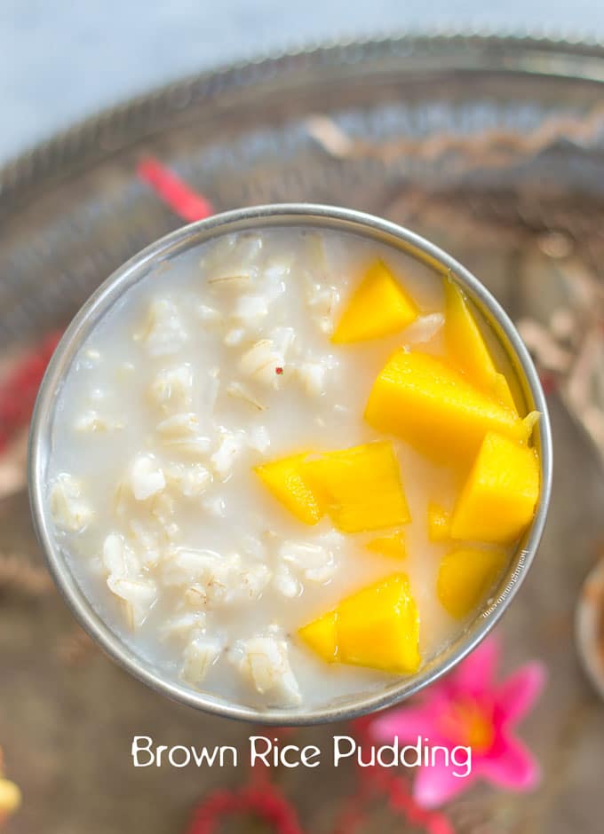 Top view of brown rice pudding in a silver cup and topped with mangoes
