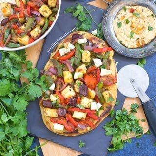 Overhead and Closeup view of Naan Paneer Pizza and surrounded by Cilantro, Hummus and spices