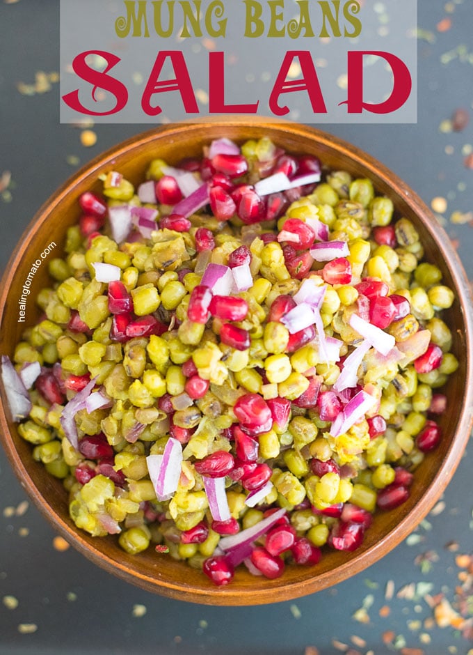 Overhead view of a wooden brown bowl filled with mung beans, pomegranate and onions