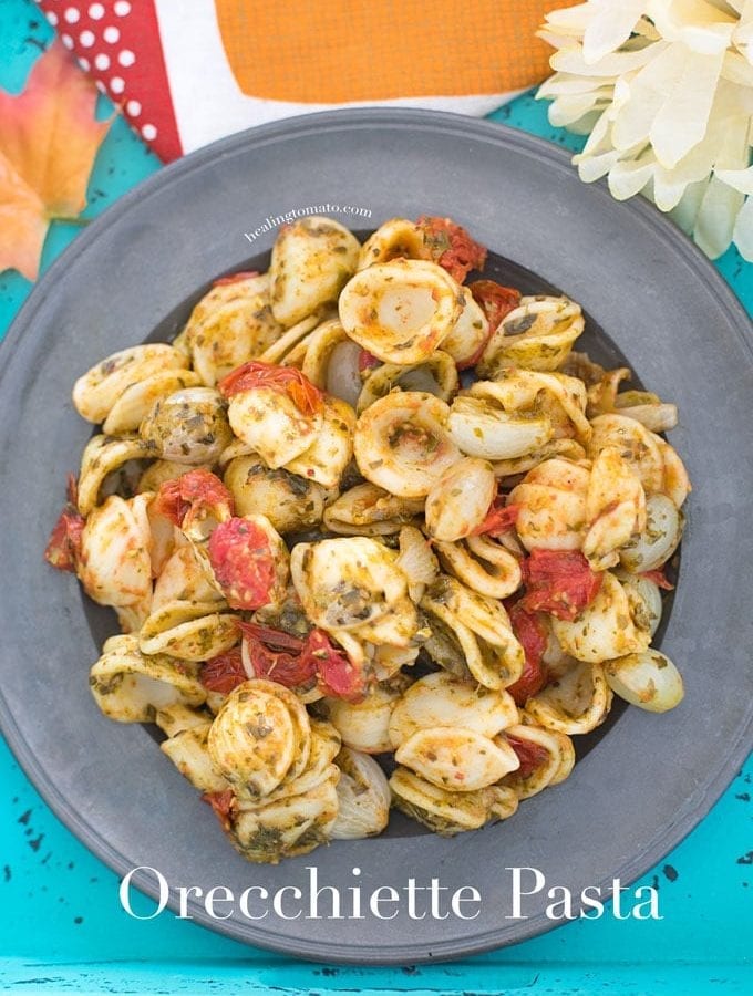 Closeup view of a grey plate filled with Vegan Orecchiette Pasta, roasted tomatoes and pearl onions