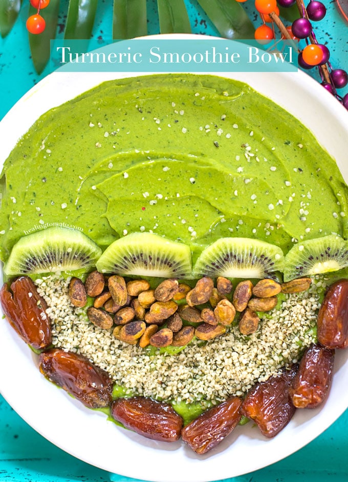 Closeup View of a Turmeric Smoothie Bowl with Green Smoothie on one half. The other half has Kiwi, Pistachios, Dates and Hemp Seeds
