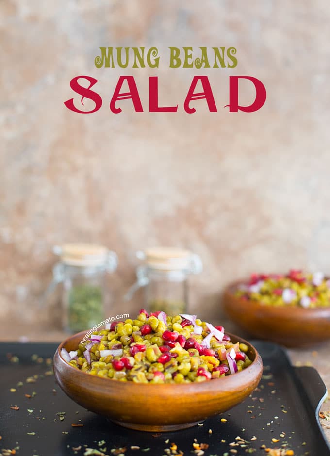 Front view of a wooden brown bowl filled with mung beans, pomegranate and onions