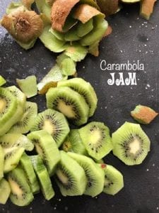 Kiwi rounds on a black chopping board with the removed skin on the side - Star Fruit Carambola