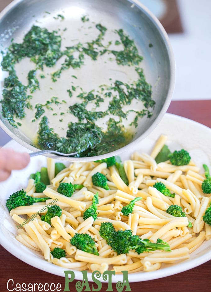 The Author powering the vegan butter sauce on the bowl of cooked casarecce pasta and rapini 