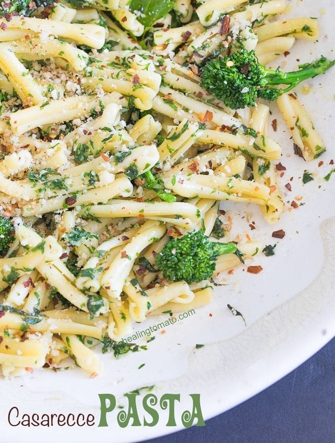 Closeup view of a white bowl filled with casarecce pasta, roasted broccolini, vegan butter sauce and panko bread crumbs as garnish