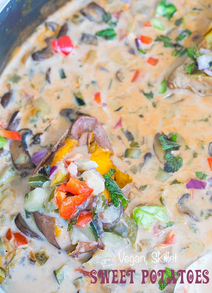 Closeup view of a baby sweet potato loaded with roasted veggies resting in a creamy sauce - Skillet Sweet Potatoes