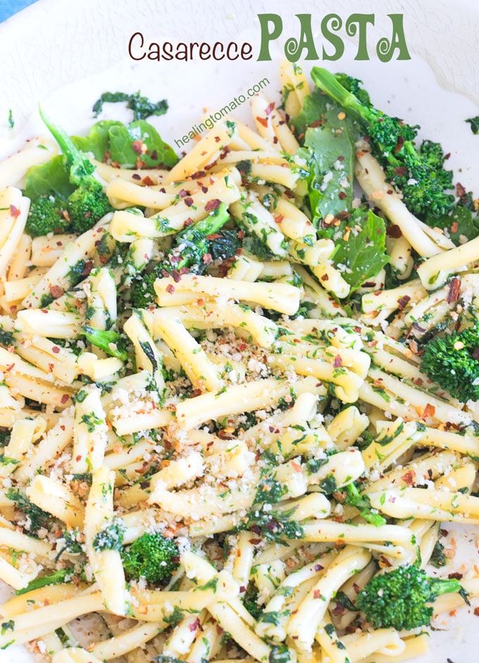 Closeup view of a white bowl filled with casarecce pasta, roasted broccolini, vegan butter sauce and panko bread crumbs as garnish