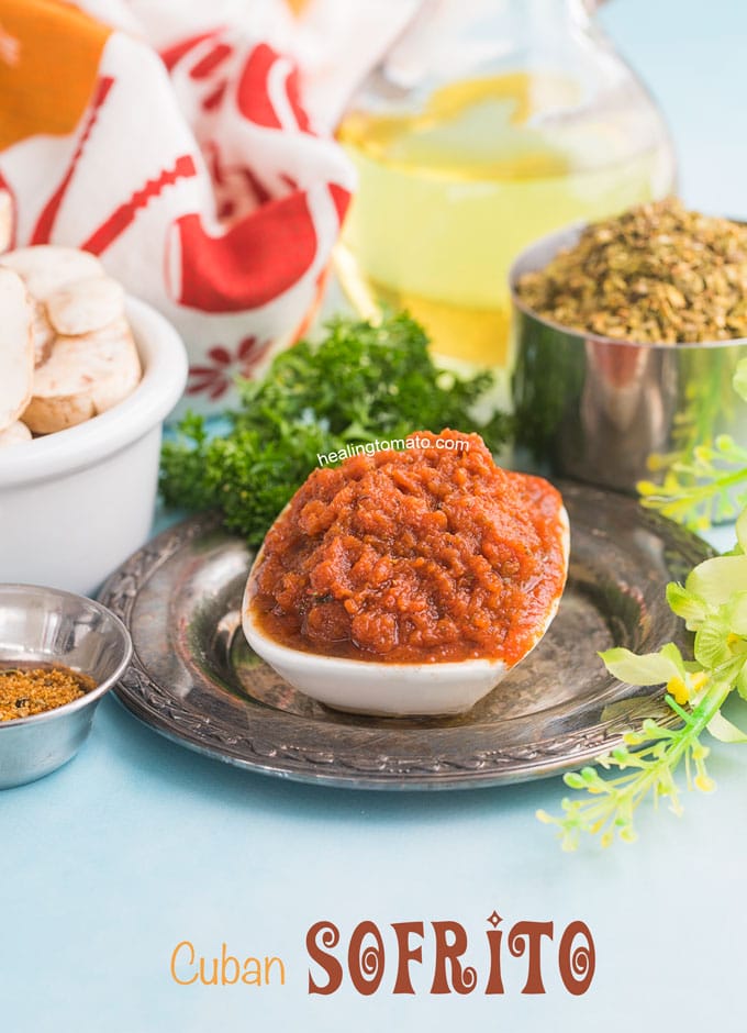 Front view of a white bowl filled with sofrito and surrounded by Oregano bowl, mushroom bowl, curley parsley and Cuban Seasoning