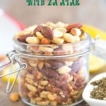 Front view of Mixed Nuts with Za'atar spice in a mason jar. Surrounded by za'atar spice and lemon rounds