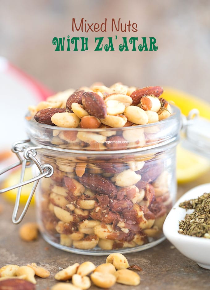Front view of Mixed Nuts with Za'atar spice in a mason jar. Surrounded by za'atar spice and lemon rounds. Best Za'atar Recipes
