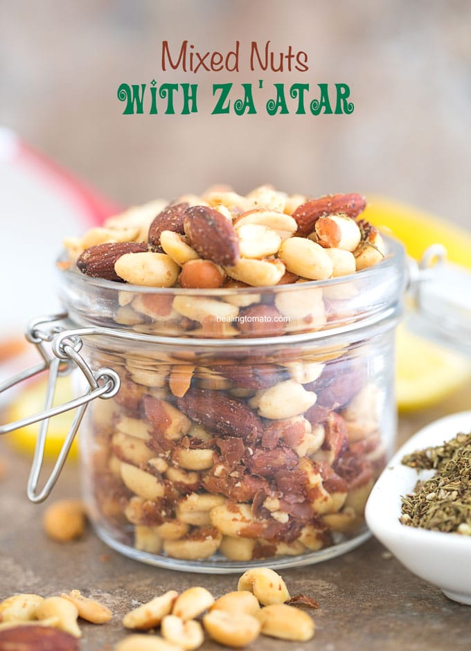 Front view of Mixed Nuts with Za'atar spice in a mason jar. Surrounded by za'atar spice and lemon rounds