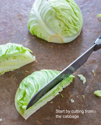 Quartered cabbage being cut into strip - Cabbage Curry
