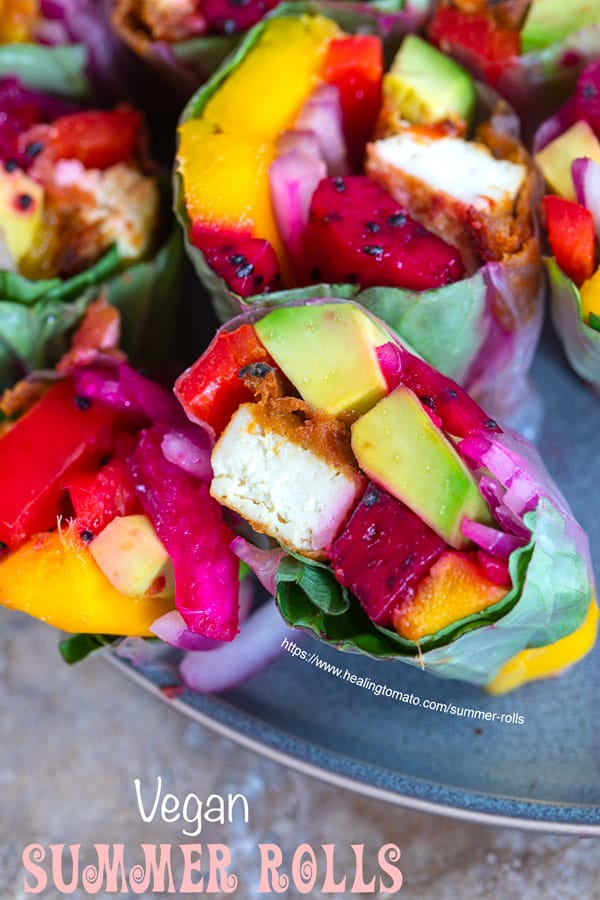 Overhead and closeup view of one cut summer rolls showing dragon fruits, avocado, tofu, onions and mango.