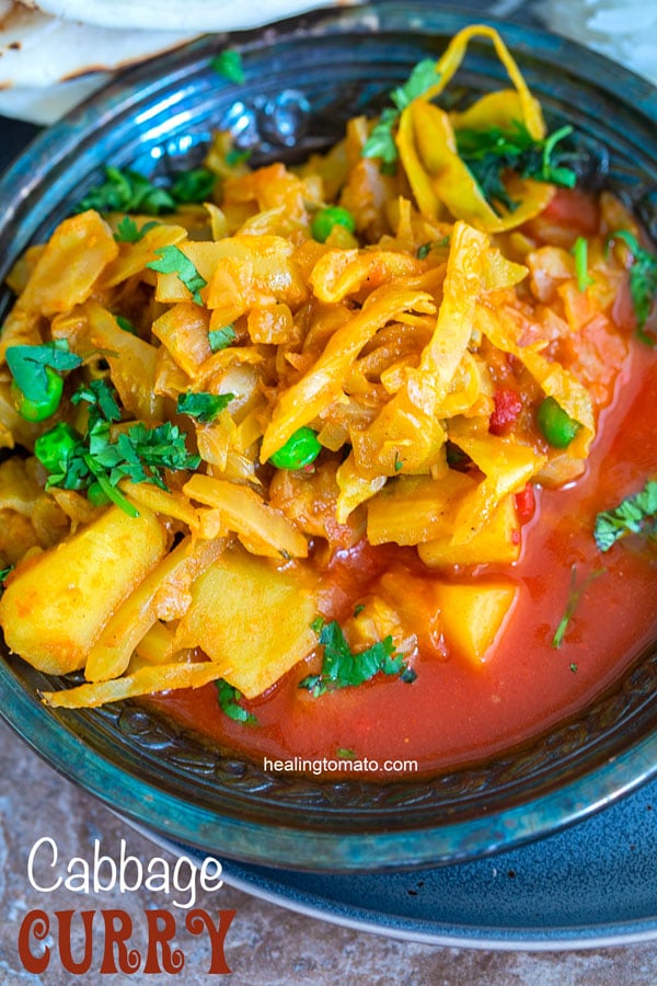 Overhead view of a metallic grey bowl filled with cabbage curry in a red sauce. Vegan Cabbage Curry