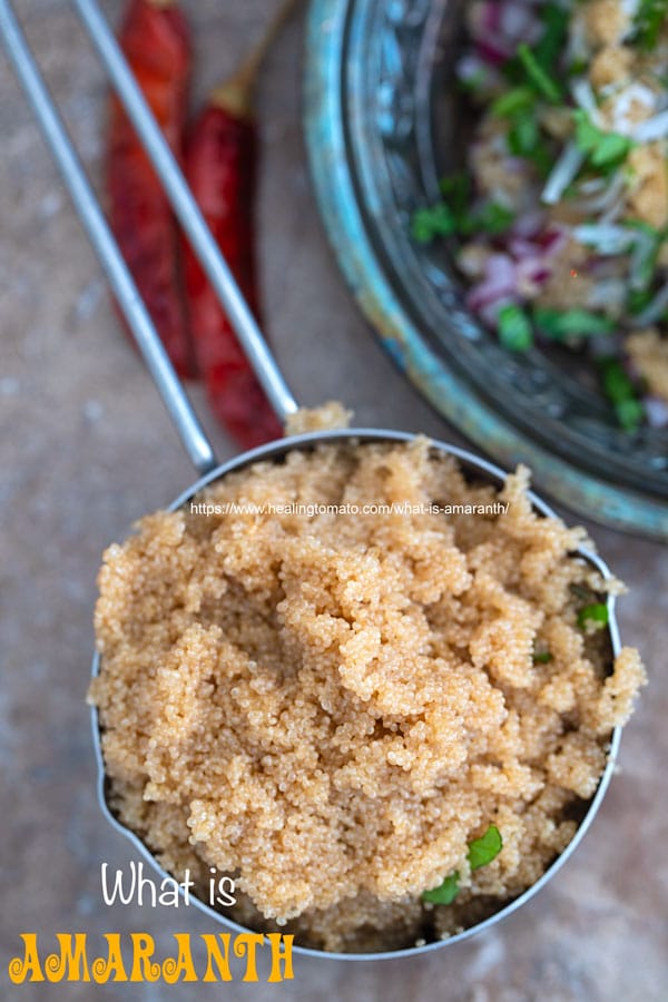 A stainless steel 1 cup measuring cup filled with cooked amaranth and a few dry red chilies next to it. An amaranth salad on the other side