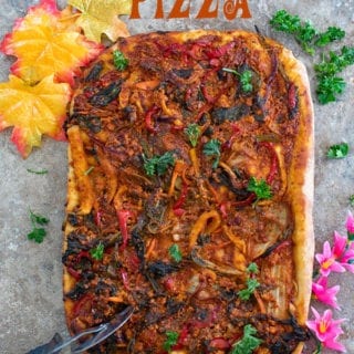Overhead view of a whole kimchi pizza with a pizza cutter on the side