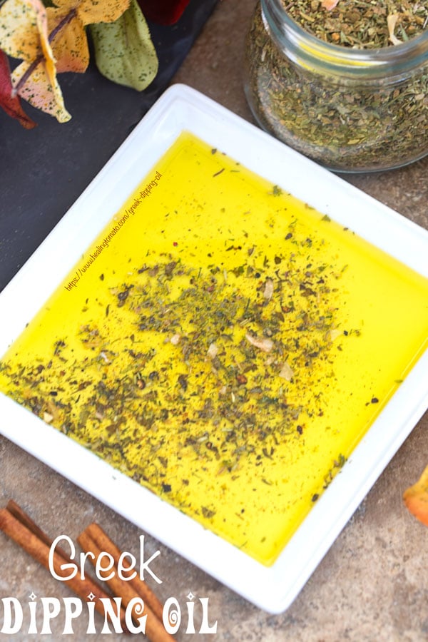 Overhead view of a white plate with Greek seasoning mix surrounded by Autumn leaves and a jar of Greek Seasoning mix 