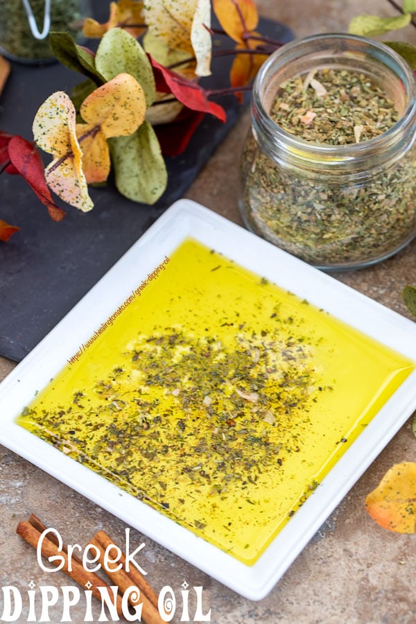 Overhead view of a white plate with Greek seasoning mix surrounded by Autumn leaves and a jar of Greek Seasoning mix 