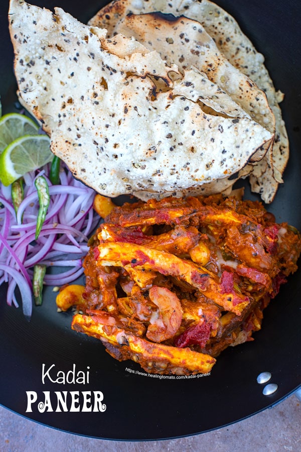 Overhead view of kadai paneer with papad and onions