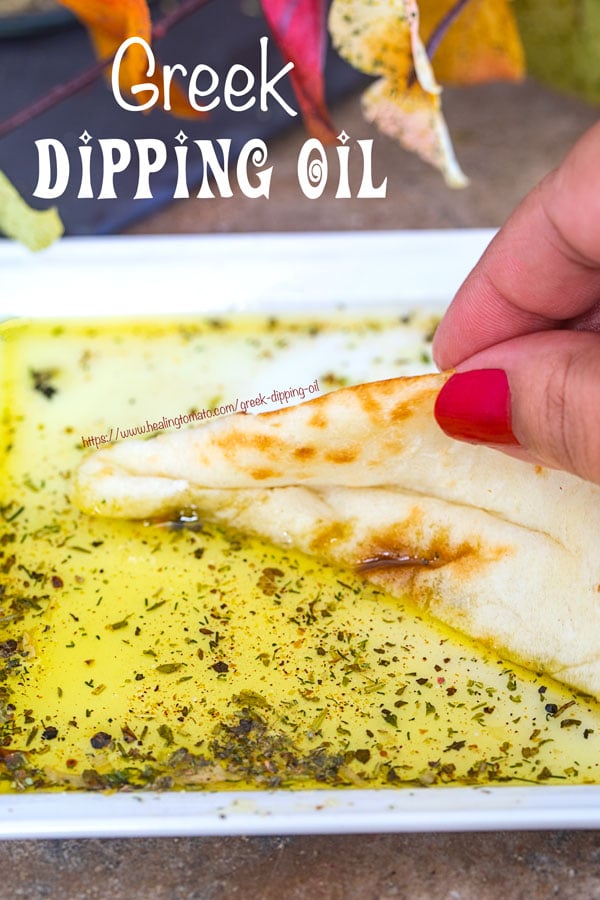The Author's hand holding a piece of pita bread on the greek dipping oil. 