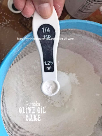 ¼ tsp filled with baking powder placed on top of a blue sieve - Vegan Pumpkin Olive Oil Cake