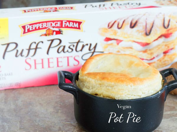 Front view of a tiny black pot filled with vegan pot pie and puff pastry in the background